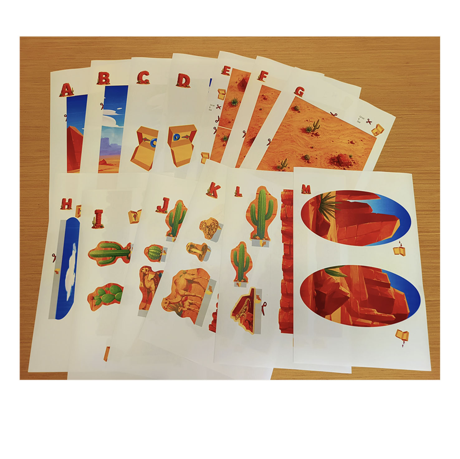 Printed Desert Habitat PDF pages laid out on a table ready for a children's craft project