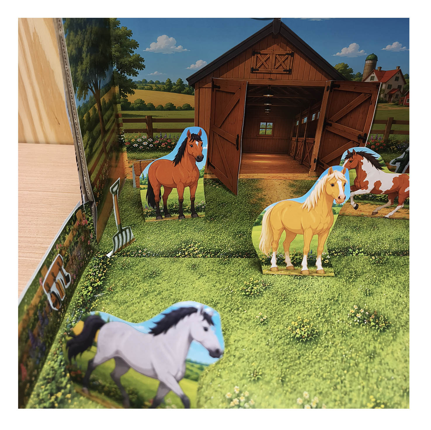 Close-up of paper horses beside the wooden stable with open barn doors in the finished printable horse diorama